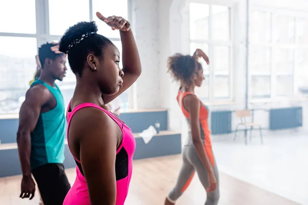 Focus selettivo di ballerini afroamericani che praticano zumba con allenatore in studio di danza — Foto stock