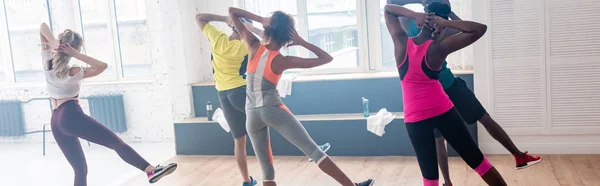 Vue arrière des danseurs de zumba multiculturels qui s'échauffent avant de s'entraîner en studio, prise de vue panoramique — Photo de stock