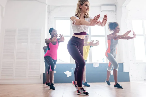 Smiling multicultural dancers performing movements of zumba in studio — Stock Photo