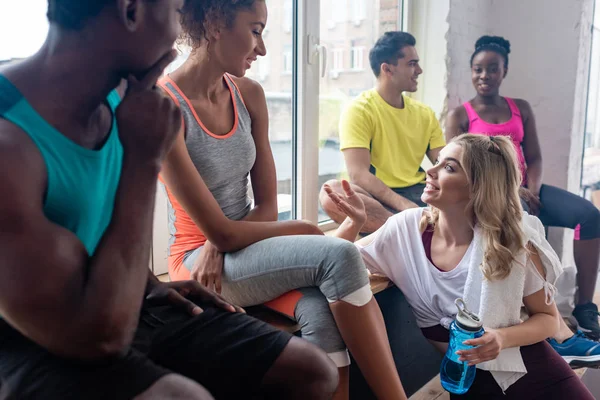 Foco seletivo de dançarinos de zumba multiétnicos conversando enquanto descansam no estúdio de dança — Fotografia de Stock