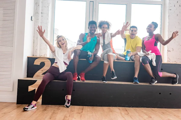 Sonrientes bailarines multiétnicos de zumba saludando a cámara en estudio de baile - foto de stock