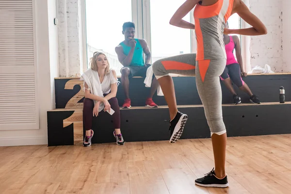 Selective focus of woman exercising with multiethnic zumba dancers on bench in dance studio — Stock Photo