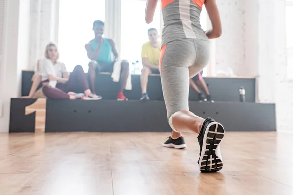 Foco seletivo da menina que aquece com dançarinos de zumba multiculturais no banco no estúdio de dança — Fotografia de Stock