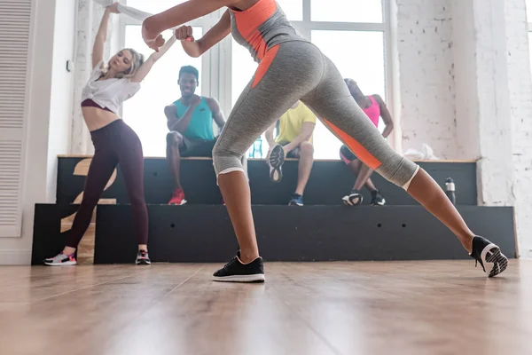 Vista de baixo ângulo de dançarinos zumba multiculturais aquecendo no estúdio de dança — Fotografia de Stock