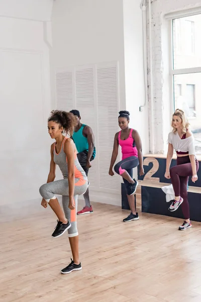 Attractive african american trainer performing zumba with multicultural dancers in dance studio — Stock Photo