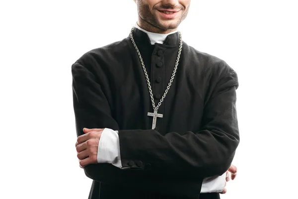 Vue recadrée du prêtre catholique souriant debout avec les bras croisés isolés sur blanc — Photo de stock
