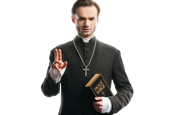 Confiant, prêtre catholique strict tenant la bible sainte et montrant geste de bénédiction isolé sur blanc — Photo de stock