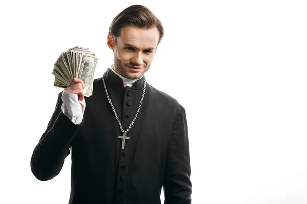 Korrupter katholischer Priester lächelt in die Kamera, während er Dollarnoten isoliert auf weißem Grund hält — Stockfoto