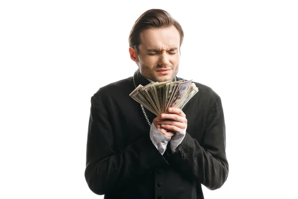 Corrupt catholic priest with closed eyes holding dollar banknotes isolated on white — Stock Photo