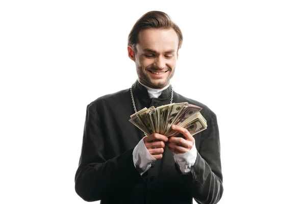 Padre católico corrupto sorrindo enquanto segurava notas de dólar isoladas em branco — Fotografia de Stock