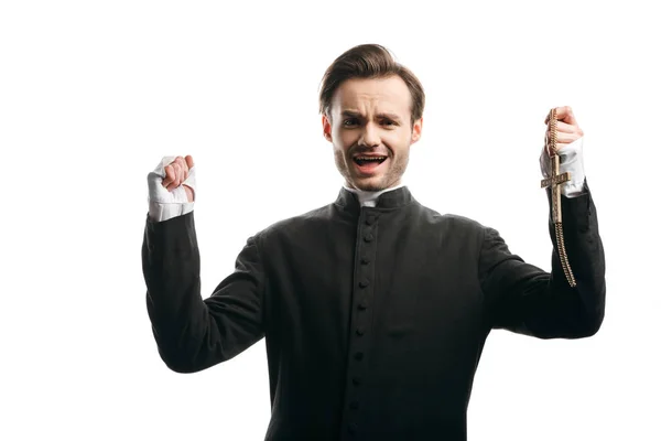 Angry catholic priest screaming at camera while holding raised fist and golden cross isolated on white — Stock Photo