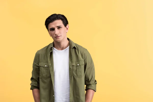 Pensive brunette young man, isolated on yellow — Stock Photo