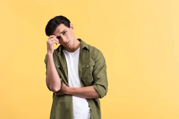 Thoughtful brunette young man, isolated on yellow — Stock Photo