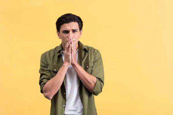 Portrait of shocked young man holding hands together, isolated on yellow — Stock Photo