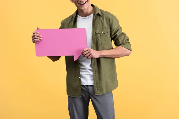 Vista ritagliata dell'uomo felice che tiene la bolla rosa di discorso, isolata su giallo — Foto stock