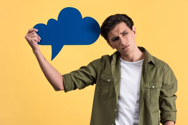 Sad man holding blue cloud speech bubble, isolated on yellow — Stock Photo