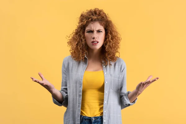 Worried redhead girl with shrug gesture, isolated on yellow — Stock Photo