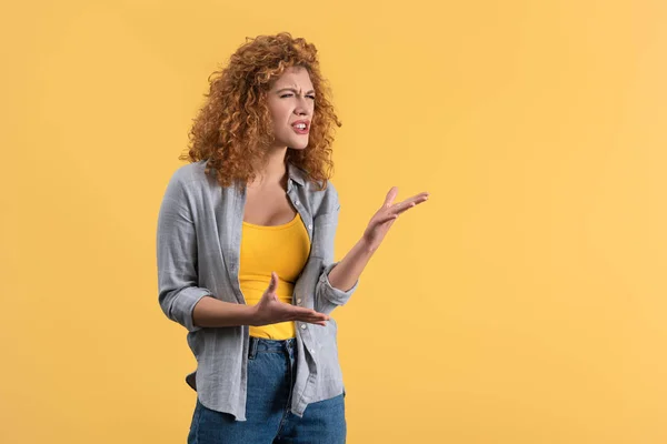 Aggressive emotional redhead girl, isolated on yellow — Stock Photo