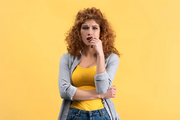 Besorgte rothaarige junge Frau, isoliert auf gelb — Stockfoto