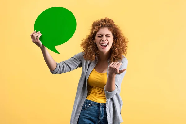 Mulher estressada segurando bolha discurso verde vazio, isolado em amarelo — Fotografia de Stock