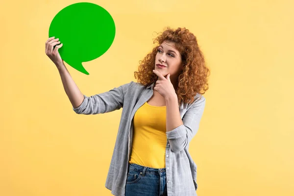 Donna pensierosa guardando vuota bolla discorso verde, isolato su giallo — Foto stock