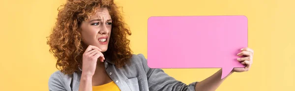 Colpo panoramico di ragazza spaventata guardando vuota bolla discorso rosa, isolato su giallo — Foto stock