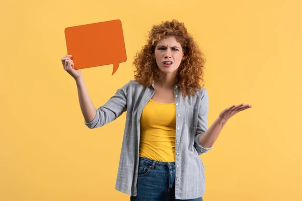 Mujer estresada sosteniendo burbuja de habla naranja vacía, aislada en amarillo - foto de stock