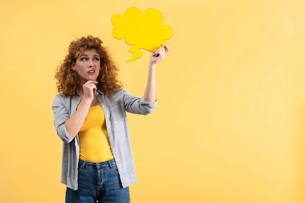 Schöne skeptische Frau sieht leere Sprechblase in Form einer Wolke, isoliert auf gelb — Stockfoto