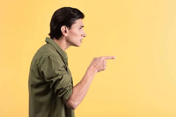 Aggressivo giovane uomo che punta isolato sul giallo — Stock Photo