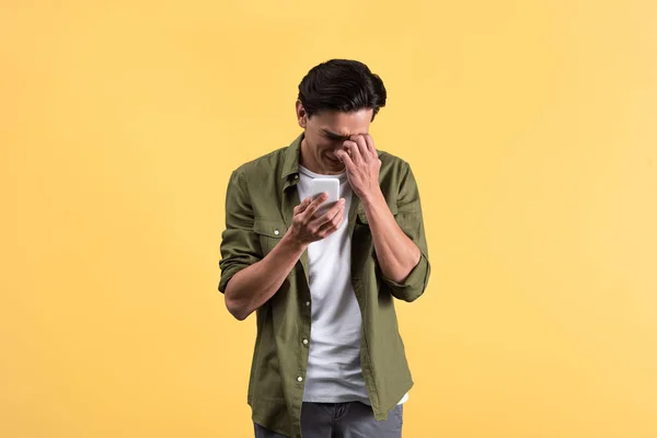 Llanto emocional joven usando teléfono inteligente, aislado en amarillo - foto de stock