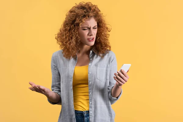 Mujer estresada enojada usando teléfono inteligente, aislado en amarillo - foto de stock