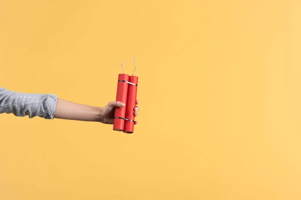 Cropped view of woman holding dynamite in hand, isolated on yellow — Stock Photo