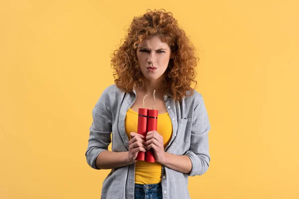 Aggressive redhead woman holding dynamite, isolated on yellow — Stock Photo