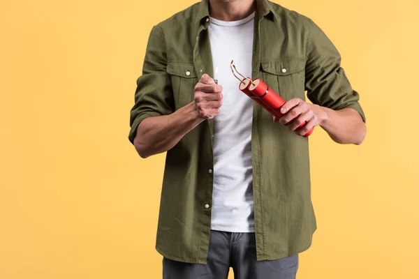 Cropped view of young man holding dynamite and lighter, isolated on yellow — Stock Photo