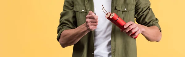 Panoramic shot of man holding dynamite sticks and lighter, isolated on yellow — Stock Photo