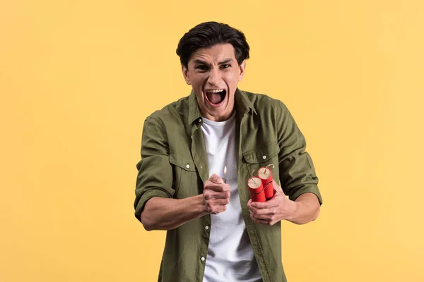 Aggressive young man shouting and holding dynamite sticks and lighter, isolated on yellow — Stock Photo