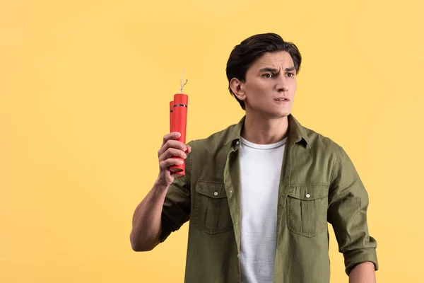 Stressed young man holding dynamite, isolated on yellow — Stock Photo