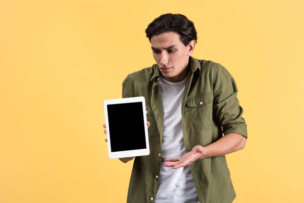 Розчарований чоловік, що показує цифровий планшет з порожнім екраном, ізольований на жовтому — стокове фото
