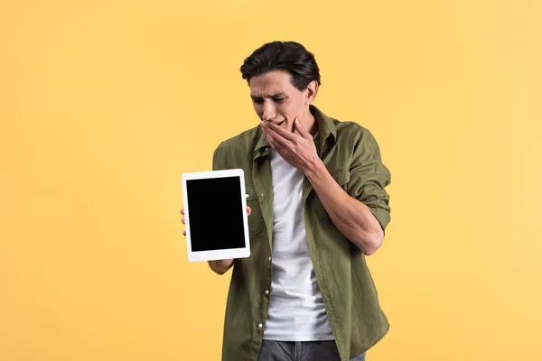 Hombre preocupado mostrando tableta digital con pantalla en blanco, aislado en amarillo - foto de stock