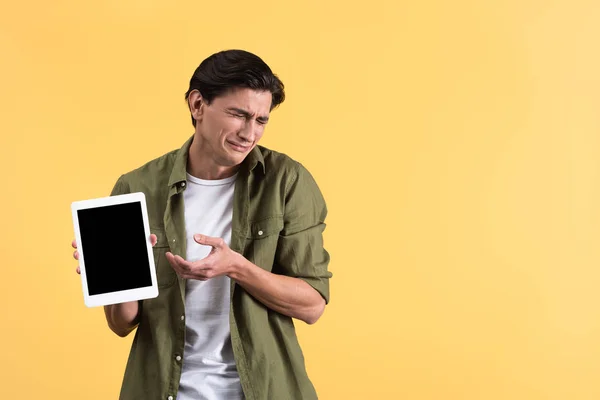 Печальный плачущий мужчина показывает цифровой планшет с пустым экраном, изолированный на желтый — стоковое фото