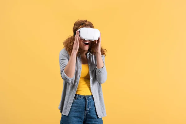 Menina ruiva animado usando fone de ouvido realidade virtual, isolado no amarelo — Fotografia de Stock