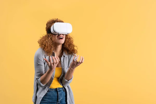 Menina ruiva emocional usando fone de ouvido realidade virtual, isolado no amarelo — Fotografia de Stock