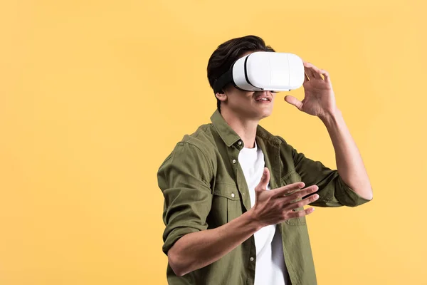 Jovem irritado gesticulando ao usar fone de ouvido vr, isolado em amarelo — Fotografia de Stock