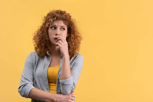 Portrait of pensive redhead young woman, isolated on yellow — Stock Photo