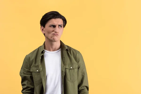 Skeptical thoughtful young man, isolated on yellow — Stock Photo
