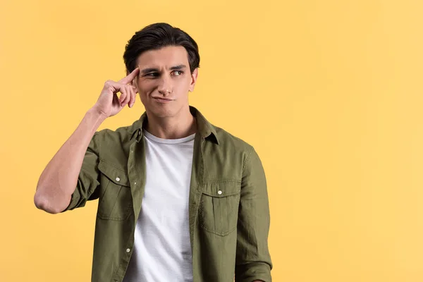 Skeptical brunette young man thinking isolated on yellow — Stock Photo