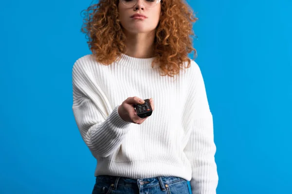 Corte vista de menina segurando controle remoto e assistindo tv, isolado em azul — Fotografia de Stock