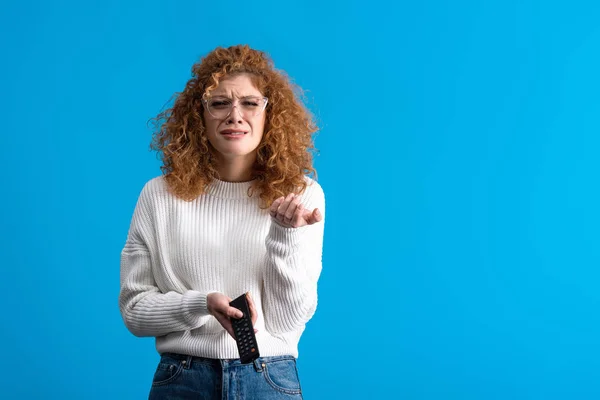 Triste fille pleurer, tenant télécommande et regarder la télévision, isolé sur bleu — Photo de stock