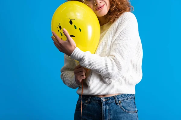 Vista ritagliata di triste rossa ragazza con palloncino giallo con viso piangente, isolato su blu — Foto stock
