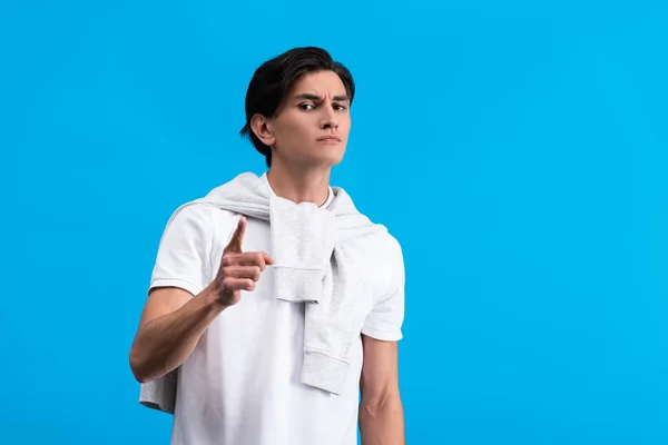 Irritated young man pointing isolated on blue — Stock Photo